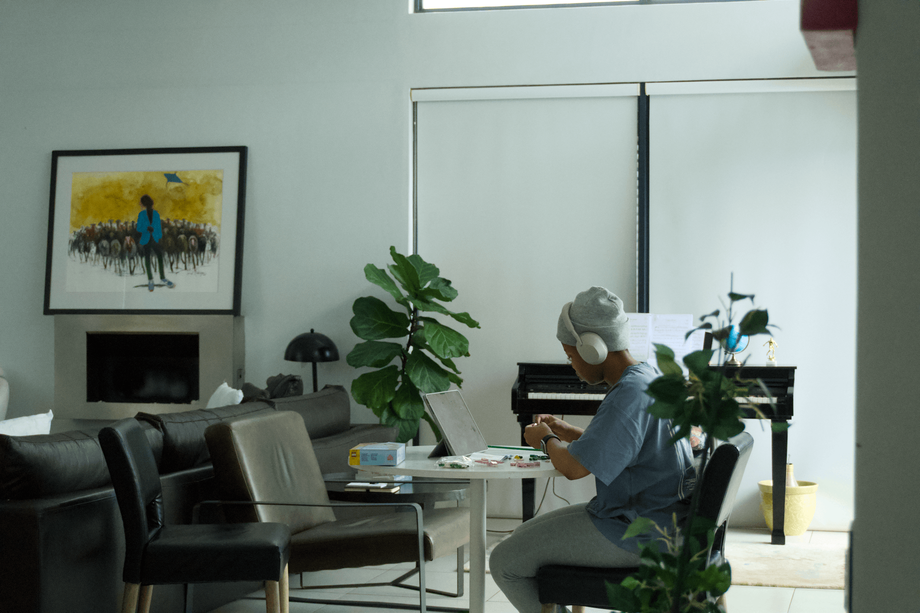 A person sitting at a desk in a well lit room, studying and listening to music on their headphones
